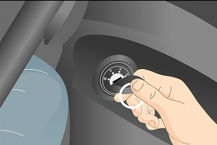 The image shows a close-up view of a person's hand turning an ignition switch on a truck's dashboard. The image is showing fingers grasping a small, round dial designed for ignition control. The dashboard around the switch is shaded in grey, focusing attention on the ignition dial and person’s hand.